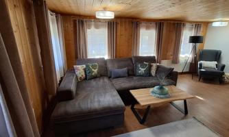 A cozy living room with a large gray sofa and a wooden coffee table. Bright windows create a cheerful atmosphere.