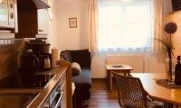A cozy kitchen with a dining area and a sofa. Bright windows bring light into the space.