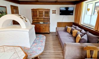 A cozy living space with a large sofa and a rustic wooden dresser. The room is bright and cheerful with plenty of natural light.
