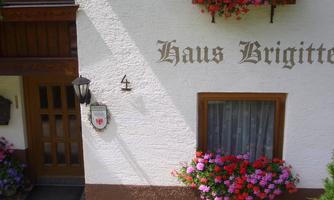 A charming house with the inscription "Haus Brigitte" and colorful flower boxes. The facade is bright and inviting.