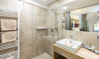A modern bathroom with a clear shower and an elegant wood sink unit. The walls are in neutral tones, creating a calm atmosphere.