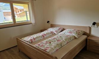 A cozy bedroom with a double bed and colorful bedspreads. Large window with a view of the surrounding landscape.
