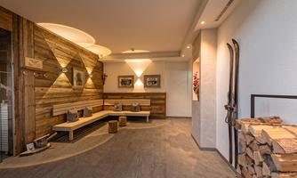 A cozy reception area with wooden decor and comfortable benches. There are decorative skis and a woodpile on the wall.