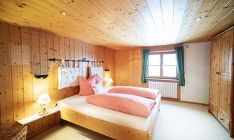 A cozy bedroom with wood paneling and two beds. The windows are equipped with curtains and there is ambient lighting.