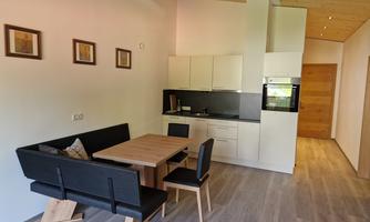 A modern kitchen with a dining table and chairs. The wooden floor and bright walls create an inviting atmosphere.