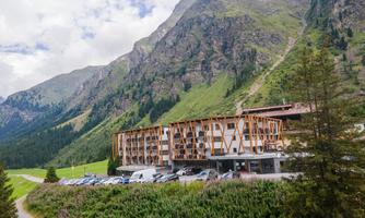 A modern hotel in the midst of an impressive mountain landscape. Green meadows and mighty mountains surround the accommodation.