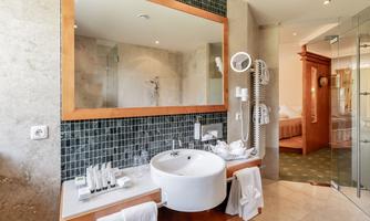 A modern bathroom with a round sink and elegant fixtures. In the background, a shower and a cozy space are visible.