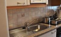 A modern kitchen with a sink and a microwave oven. Cookware is on the countertop and the floor is clean.