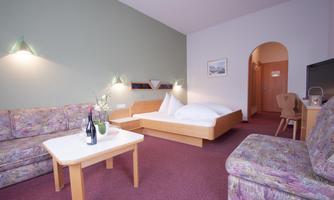 A cozy room with a double bed and a seating area. The space is bright and inviting, with modern comfort.