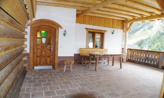 A cozy balcony with wooden cladding and a table. The mountains are visible in the background.