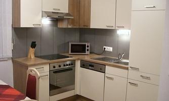 A modern kitchen with bright cabinets and a cooking area. It features a stove, a refrigerator, and a microwave.