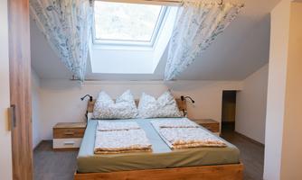 A cozy bedroom with a double bed and large pillows. Natural light flows into the room through the skylight.