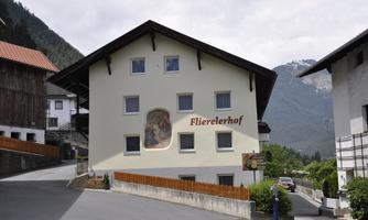 A charming building with a mural and the inscription "Fliererlhof." In the background, the mountains and typical alpine landscapes are visible.