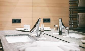 A modern bathroom with two sinks and a wood-look wall. Towels and toiletries are neatly arranged.