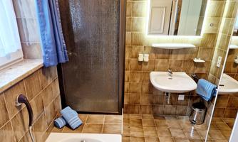 A modern bathroom with a bathtub, a shower, and a sink. The walls are painted in warm earth tones, and there are soft towels in blue.