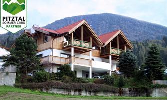 A beautifully designed house in the mountains with wooden construction elements and red roofs. Surrounded by trees and meadows, it offers a picturesque view.