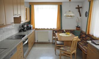 A spacious kitchen with wooden cabinets and modern appliances. A dining table with chairs and a cozy seating area invites you to linger.