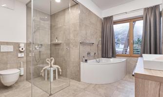 A modern bathroom with a glass shower and an oval bathtub. Large windows provide plenty of daylight and a pleasant atmosphere.