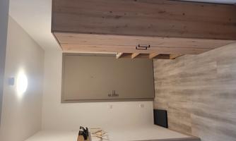 A bright hallway with wooden shelves and a closed entrance. The walls are painted in neutral colors and the floor is made of light planks.