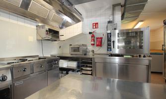 A modern kitchen with stainless steel appliances and various cooking surfaces. The environment is clean and well-organized.