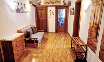 A cozy hallway with wooden furniture and warm lighting. A light wood parquet floor lies on the ground.