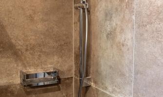 A modern shower with a handheld showerhead and elegant tiles. The walls are designed in brown and beige tones.