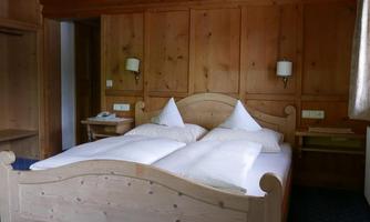 A cozy bedroom with a large wooden bed and two pillows. The walls are made of wood and there is a blue carpet.