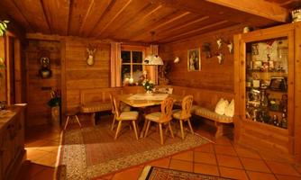 Cozy wooden room with a dining area and a display cabinet. The warm colors and decorations create an inviting atmosphere.