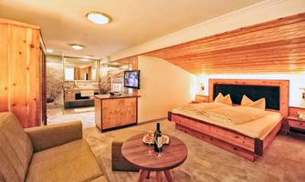 A cozy room with a double bed and a television. The wooden paneling creates a warm atmosphere, while a seating area invites you to relax.