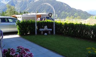 A beautiful view of the mountains with a well-kept garden. In the foreground are colorful flowers and a small seating area.