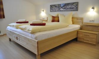 A cozy bedroom with a large wooden bed and fresh bedding. The walls are bright and there is a comfortable ambiance.