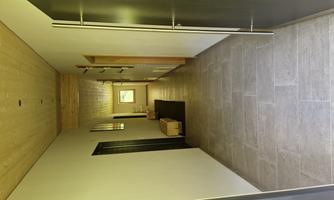 A bright hallway with modern doors and gray tiles. At the end of the hallway is a window that lets in daylight.