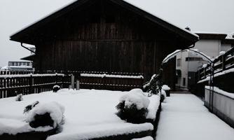 A large wooden house in the snow with a covered entrance. The garden is covered with a thick layer of snow.