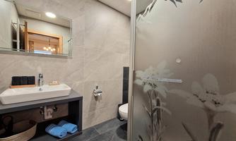 A modern bathroom with an elegant shower and sink. The walls are in neutral colors, creating a calm atmosphere.