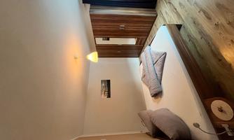 A modern bedroom with a double bed and wooden floor. The room has a wardrobe and plenty of natural light.