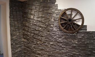 A stylish wall made of dark stones with a decorative wagon wheel. The combination creates a rustic and inviting atmosphere.