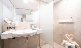 A modern bathroom with a sink, a mirror, and a walk-in shower. Bright tiles and stylish decor create an inviting atmosphere.