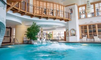 An elegant indoor pool with clear water and wooden paneling. Large windows allow plenty of daylight in and create a relaxed atmosphere.