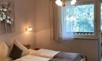A cozy bedroom with two beds and pleasant lighting. The window offers a view of nature.