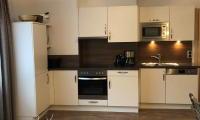 A modern kitchen with white cabinets and wood accents. It is well-equipped with cooking appliances and has a bright, inviting atmosphere.