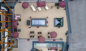 A large rooftop terrace with sun loungers and umbrellas. The area is tiled and offers space for relaxation outdoors.
