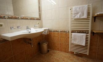 A bright bathroom with a sink and a large mirror. Towels are hanging on a radiator.