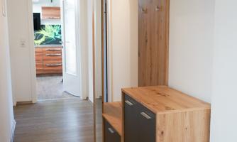A bright hallway with a modern wooden wardrobe. The room has an inviting and tidy appearance.
