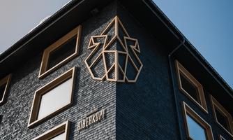 A modern building with a black facade and large windows. On the wall, there is a striking geometric design.
