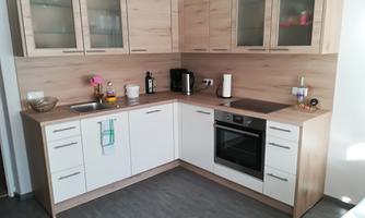 A modern kitchen with wooden and white cabinets. The equipment includes a stove, a sink, and various kitchen accessories.