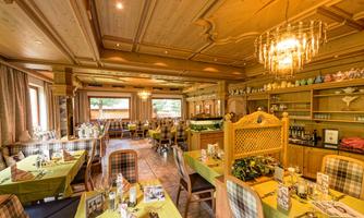 A cozy restaurant with wooden furniture and stylish lighting. The tables are beautifully set and invite you to dine.