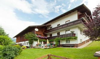 A charming building with balconies and colorful flowers. The garden is green and inviting, perfect for relaxing outdoors.
