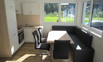 A bright kitchen with a dining area and large windows. The room is furnished in a modern style and feels friendly and inviting.