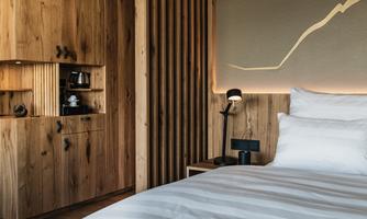 A modern bedroom with wood paneling and soft lighting. The bed is inviting, and the decor feels warm and cozy.