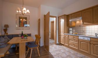 A cozy kitchen with wooden furniture and a dining table. The room is bright and inviting.